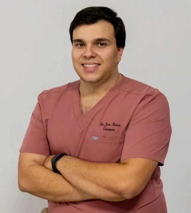 Dr. João Bessa, osteopata, de farda cor-de-rosa e braços cruzados