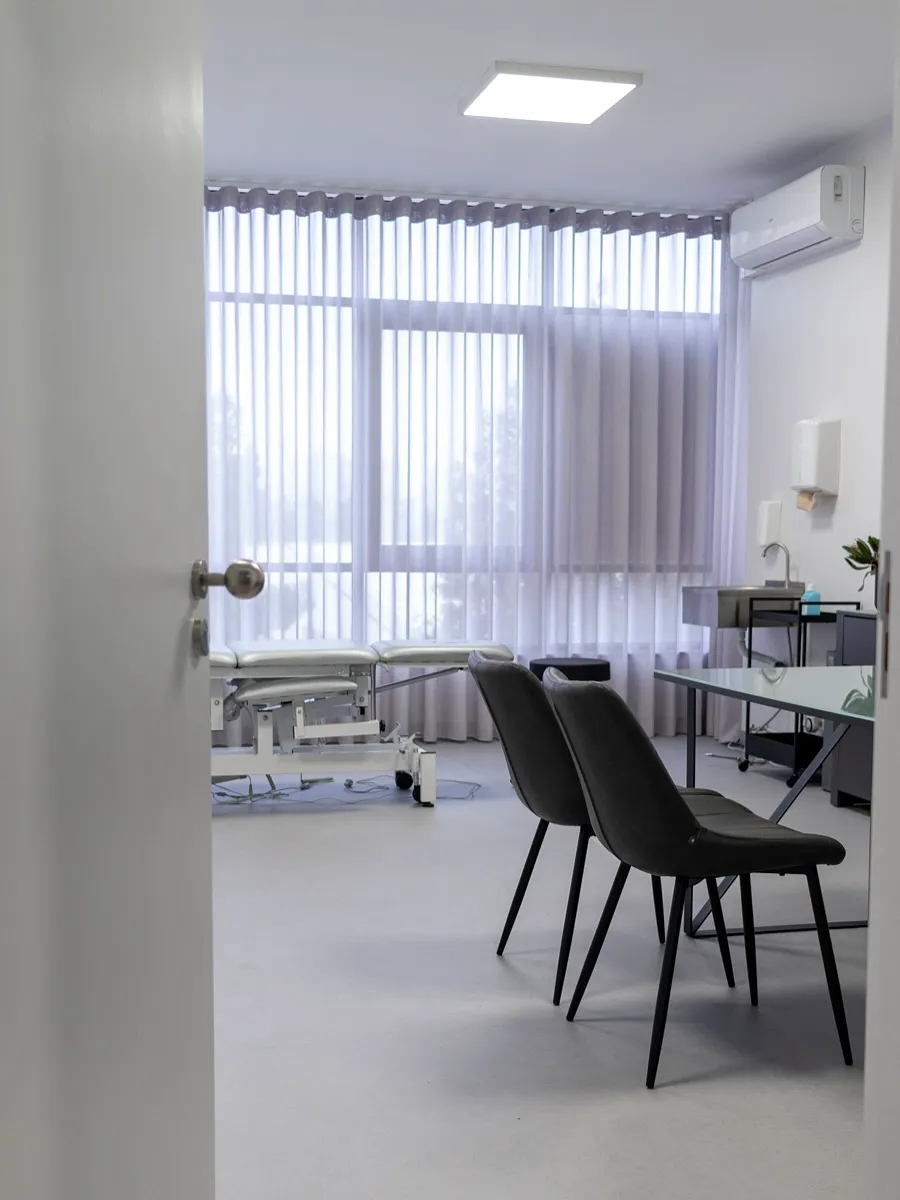 Sala de tratamento do gabinete, com marquesa, cortinas claras e luz natural